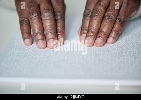 Close-up of senior blind man reading book with braille language at table Stock Photo