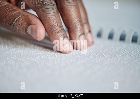Close-up of blind man running his fingers over the dots and reading braille Stock Photo