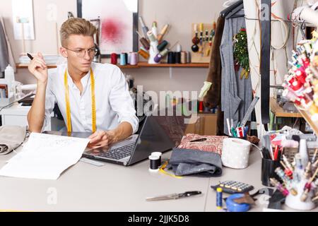 Tailor creating pattern using laptop Stock Photo