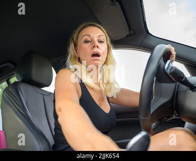 Distracted female driver using her mobile phone while driving reading a text message with her eyes taken off the road Stock Photo