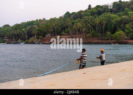 Local Indian fishermen throwing nets into the ocean in the village of Betul, Salcete, Goa, India Stock Photo