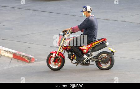 SAMUT PRAKAN, THAILAND, MAY 26 2022, A man with face mask rides a motorcycle Stock Photo