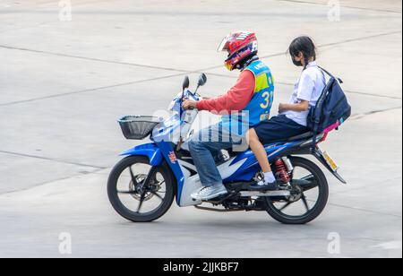 SAMUT PRAKAN, THAILAND, MAY 26 2022, A taxi driver on a motorcycle rides with a schoolgirl. Stock Photo