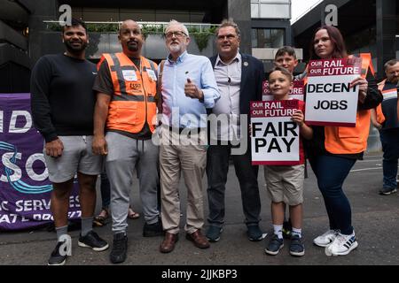 London, UK. 27th July, 2022. Jeremy Corbyn MP (3L) and RMT union members join the picket line outside Euston Station as railway workers stage a 24-hour walk-out. More than 40,000 workers from 14 train operating companies and Network Rail are taking part in the industrial action, called by the RMT (The National Union of Rail, Maritime and Transport Workers), as part of an ongoing dispute over pay, jobs and conditions following three days of strikes in June. Credit: Wiktor Szymanowicz/Alamy Live News Stock Photo
