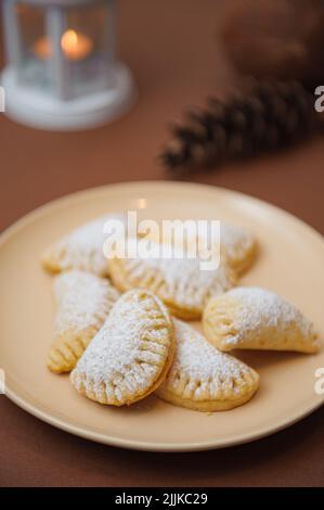 A close-up shot of sweet pastry seashells with marmalade and icing sugar in a pink plate on the table with blurred background Stock Photo
