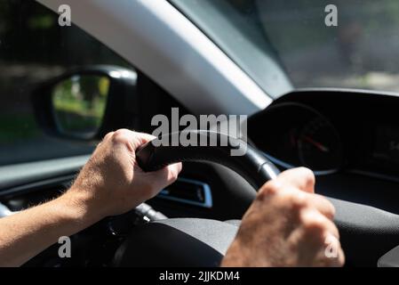 White men hands control a car steering wheel while driving on the road. There are no recognizable persons or trademarks in the shot. Stock Photo