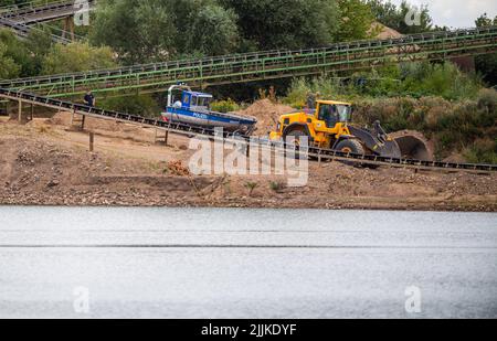 Porta Westfalica, Germany. 27th July, 2022. A police boat is pulled by a wheel loader into a gravel pond where two people failed to surface for unexplained reasons while swimming on Sunday (24.07.2022). According to a spokesman for the fire department, some parts of the lake are about 30 meters deep. Experts from the police now want to search for the two people with an underwater probe. Credit: Lino Mirgeler/dpa/Alamy Live News Stock Photo