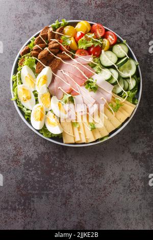 Chef salad is an American salad consisting of boiled eggs, more varieties of meat, tomatoes, cucumbers, and cheese, all placed upon a bed of tossed le Stock Photo