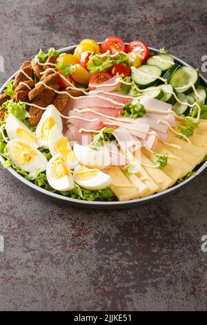 Chef salad is an American salad consisting of boiled eggs, more varieties of meat, tomatoes, cucumbers, and cheese, all placed upon a bed of tossed le Stock Photo