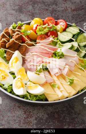 Beautiful and delectable Chef Salad with eggs. ham, cheese, fresh tomatoes, cucumbers and seasoned croutons closeup in the plate on the table. Vertica Stock Photo
