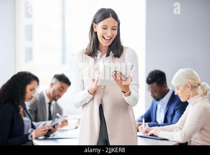 Strong leadership makes for a strong team. a beautiful young businesswoman using a digital tablet during a business meeting. Stock Photo