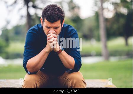 A closeup of a man sitting on a bench in a park Stock Photo