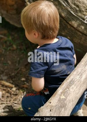 A side view of a little boy with blonde hair in the street on a sunny day Stock Photo