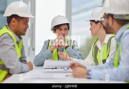 Planning it all out. a group of young construction workers sitting around the boardroom table during a meeting. Stock Photo