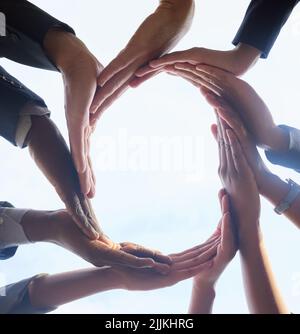 Together we keep business flowing. a group of unrecognizable businesspeople joining their hands in solidarity. Stock Photo