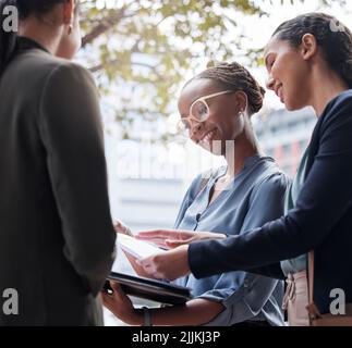 Sharing new ideas. a group of businesswomen going through paperwork against a city background. Stock Photo