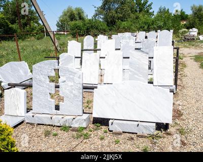 blank stone gravestones and grave slabs in outdoor rural granite workshop on sunny summer day Stock Photo