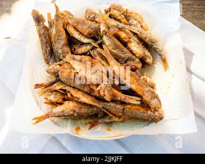 above view of fried small Black Sea surmullet fishes on white paper napkin in plate on table Stock Photo