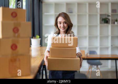 Young asian woman freelancer sme business online shopping working with parcel box at home - SME business online and delivery concept Stock Photo