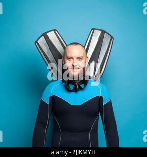 Happy diver diving man with flippers smiling against bright blue studio wall background Stock Photo
