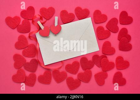 Background for your greetings for a Valentine's day. A envelope with felt hearts on the red background. Top view. Stock Photo