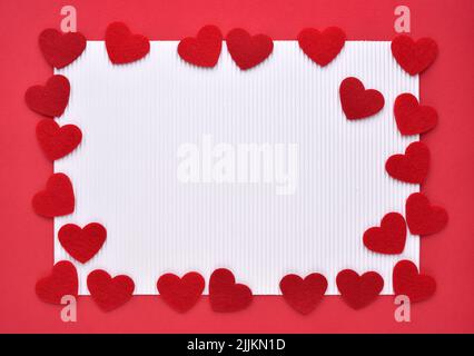 Felt hearts on red and white paper. Valentine's Day concept. Top view with copy space for text. Stock Photo