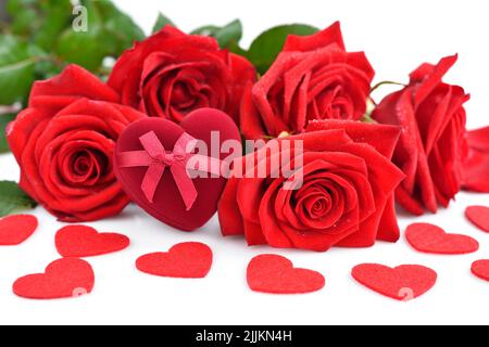 Red rose bouquet with heart-shaped gift box and red felt hearts on white background. Soft focus. Stock Photo