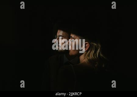 The profiles of a Caucasian male and a Middle Eastern female on dark background Stock Photo
