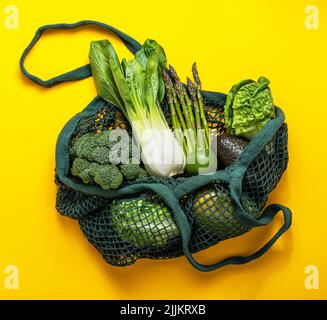 Photography of cotton bag with green, fresh vegetables on a yellow background Stock Photo