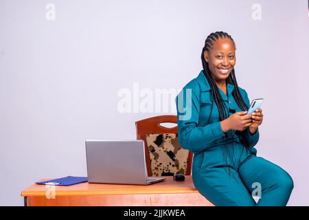An African businesswoman sitting at her office table and using the phone Stock Photo