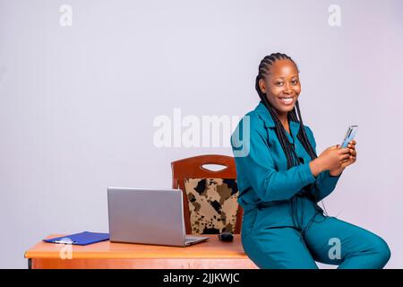 A portrait of young African beautiful woman holding smart phone, using app or chatting at workplace Stock Photo