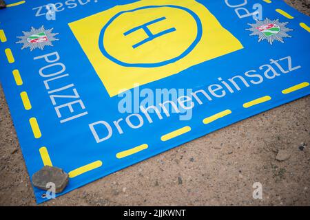 Porta Westfalica, Germany. 27th July, 2022. A launch mat for a police drone lies on the ground at the edge of the body of water where two people failed to surface for unexplained reasons while swimming on Sunday (24.07.2022). According to a spokesman for the fire department, some parts of the lake are about 30 meters deep. Experts from the police now want to search for the two people with an underwater probe. Credit: Lino Mirgeler/dpa/Alamy Live News Stock Photo