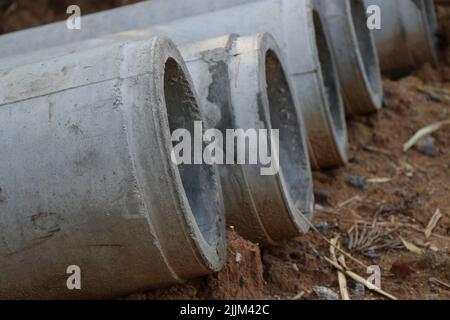 Concrete drainage pipes kept on the ground ready to be installed underground to drain water or sewage water Stock Photo