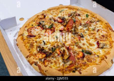 Newcastle England: 14th July 2022: Huge 14-inch spicy chicken tikka pizza from a takeaway. Very greasy in the cardboard pizza box Stock Photo