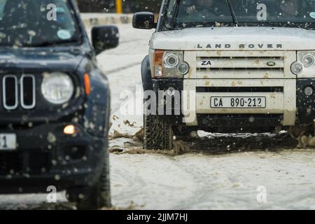 two 4x4's or SUV's one behind the other driving through water logged road showing their capabilities as off road vehicles in Cape Town, South Africa Stock Photo