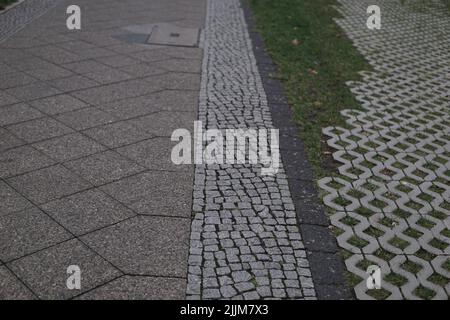 A beautiful shot of a Detailed closeup texture on a cobblestone street with different tiles and grass Stock Photo