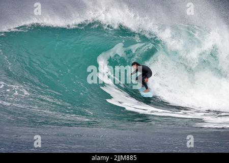 A beautiful shot of a surfer riding through the barrel in Porthleven, UK Stock Photo