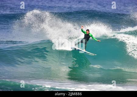 A surfer executing a cutback on a wave in Watergate Bay Stock Photo