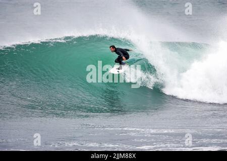 A beautiful shot of a surfer riding through the barrel in Porthleven, UK Stock Photo