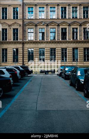 A vertical shot of the cars parked in the parking lot in front of the building. Stock Photo