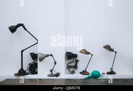 A row of different lamps on a table isolated on a white wall background Stock Photo