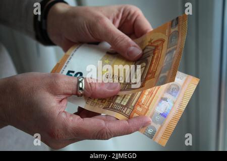 A closeup shot of a person holding two fifty euro banknotes Stock Photo