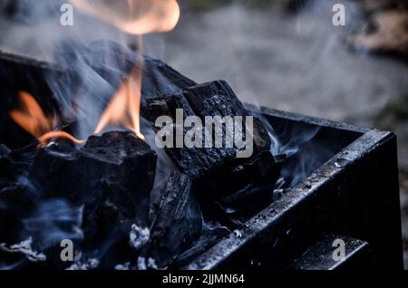 A closeup shot of the bright burning black coals in the black iron barbecue grill Stock Photo