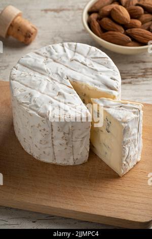 Whole French Bleu de Bresse cheese and a wedge on a cutting board close up Stock Photo