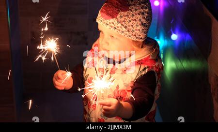 Curiously baby is holding a sparkler Stock Photo