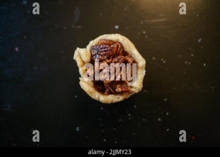 A top view of a sweet dessert with walnuts for Thanksgiving placed on a black table Stock Photo