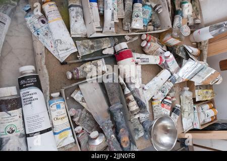 A top view of dozens of used artists paint tubes on a table Stock Photo