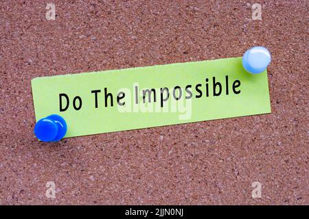 Do the impossible words on stick note and pinned to a cork notice board. Business concept. Stock Photo