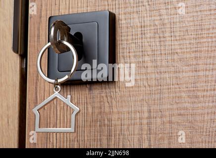 House key with house keychain in the door. Real estate property business concept Stock Photo