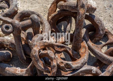 pile of rusty old chains, corroded old chains, shackles and chains on quayside, corrosion and rust on old chain links and shackles on the dockside. Stock Photo